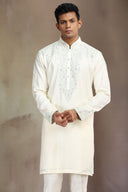 This cream silk kurta set features elegant embroidery for a sophisticated look.