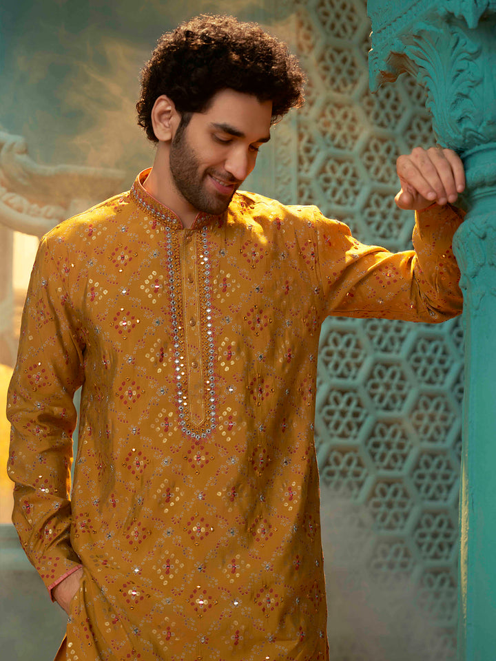 A mustard colour kurta block printed with mirror work with a maroon colour chudidar pant.